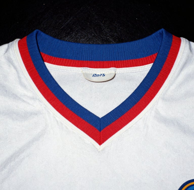 Candid 35mm film photo of a vintage football shirt collar close-up, heavy grain, harsh direct flash, authentic 90s aesthetic