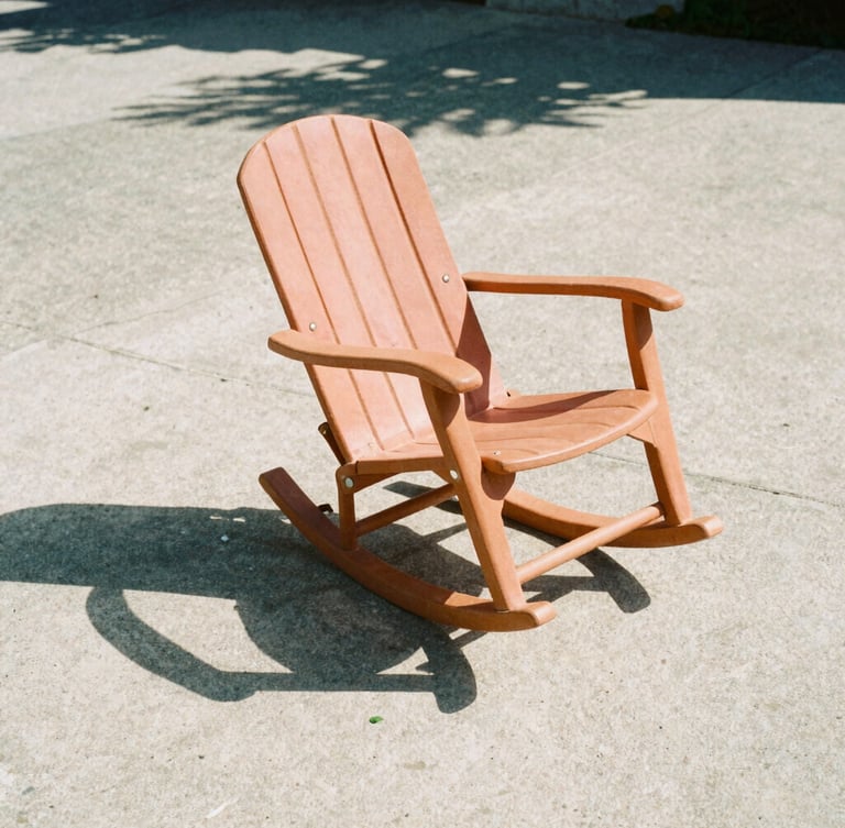 Low-angle architectural shot of a single terracotta rocker casting a sharp graphic shadow on raw concrete, harsh direct mid-afternoon sunlight, 35mm film style.