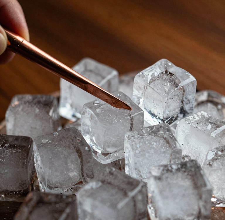 Macro shot of large clear ice cubes being carved with a copper tool, dramatic side lighting, rich warm tones of wood and copper