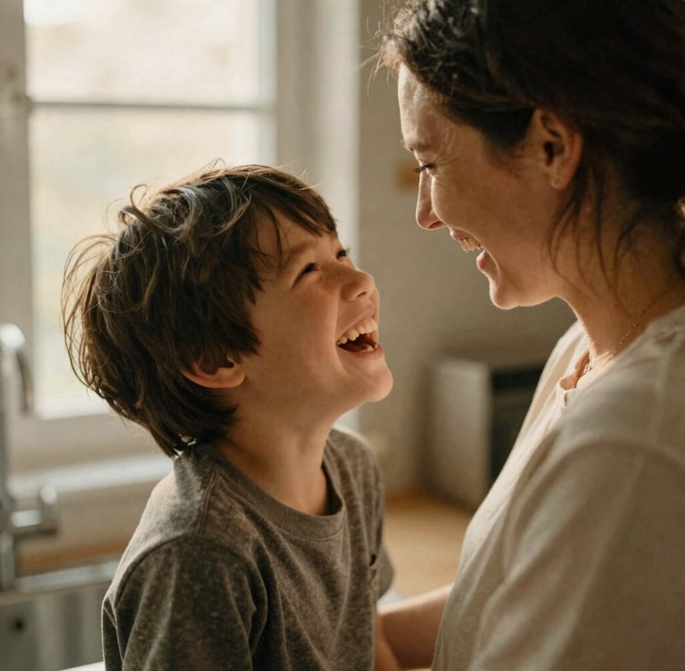 Candid medium close-up of a mother and her neurodivergent son laughing together in a warm, sunlit kitchen, soft natural window light, muted earth tones, 35mm film grain