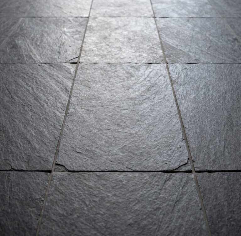 Low-angle portrait shot of pristine slate floor tiles laid in a perfect grid, natural light catching the subtle stone texture and razor-straight grout lines.