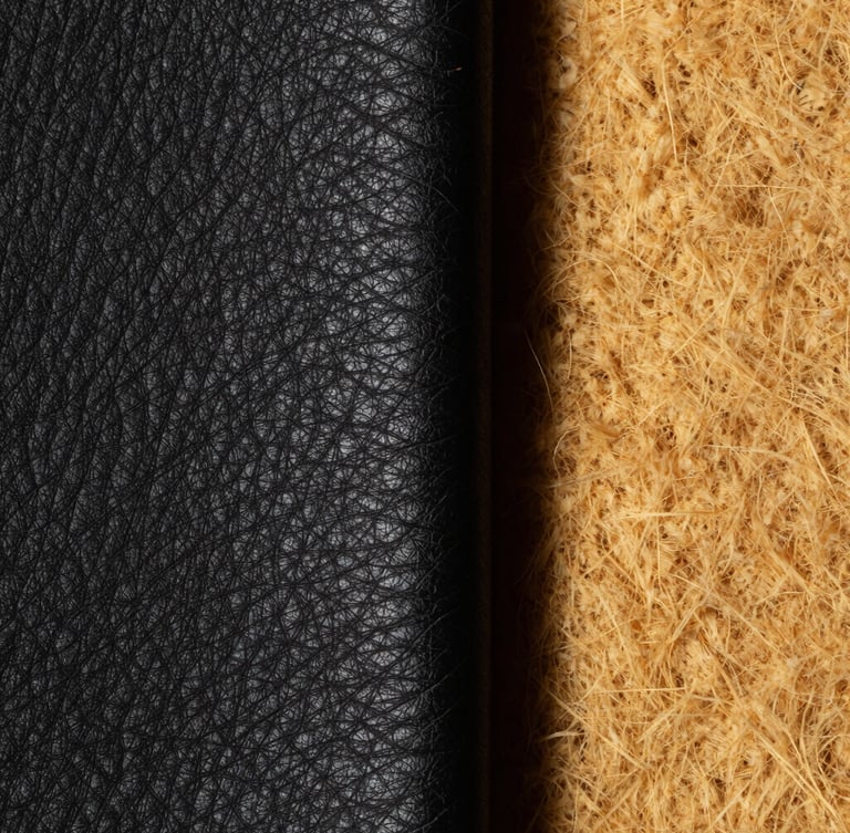 Macro studio shot of thick black full-grain leather grain next to raw textured golden wool, high contrast, deep shadows, 85mm lens