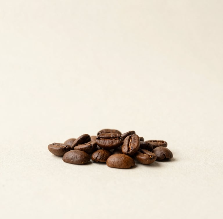 Minimalist studio photography of raw and roasted coffee beans resting on a textured off-white background, soft diffused daylight, warm earth tones, editorial composition, 50mm lens.