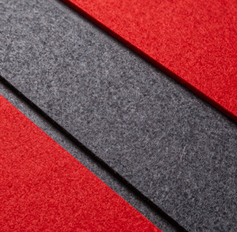 Overhead flat-lay of precision-cut synthetic felt bags and acoustic panels in vibrant red and deep gray, clean sharp studio lighting, minimal composition.