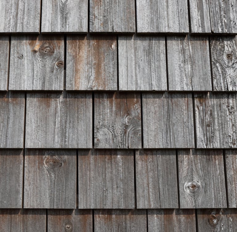 Tight close-up of interlocking cedar shake siding, showing the raw weathered wood grain and tight joints, coastal Connecticut.