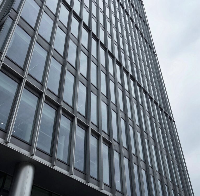 Wide architectural perspective of a modern steel and glass skyscraper facade in Wilmington, sharp geometric lines, overcast daylight, cold tones, high-end corporate permanence.