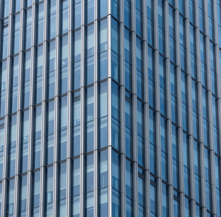 Crisp architectural photography of a modern high-rise glass facade with sharp geometric lines, cool daylight reflecting subtle royal blue tones, clean corporate minimalism.