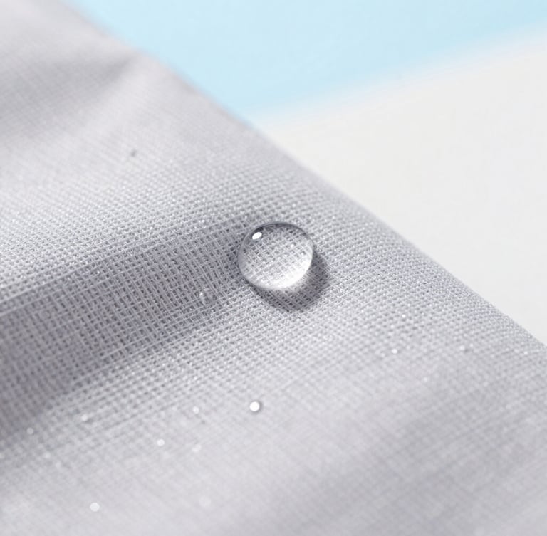 Macro close-up of water droplets beading perfectly on soft grey woven fabric, bright natural daylight, clean airy background, 35mm lens.