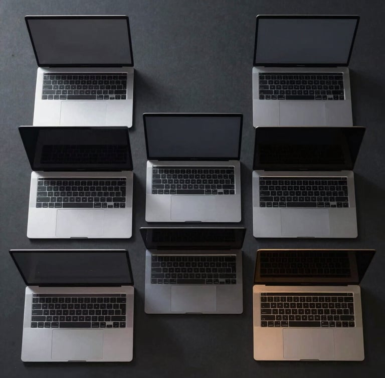 Symmetrical overhead shot of a fleet of sleek space-gray MacBook Pro laptops aligned perfectly on a dark matte surface, metallic edges catching gold light