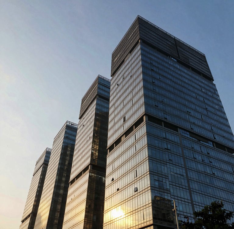 Low-angle dramatic golden hour shot of modern glass skyscrapers in Thane, light reflecting off concrete facades, negative space on the left