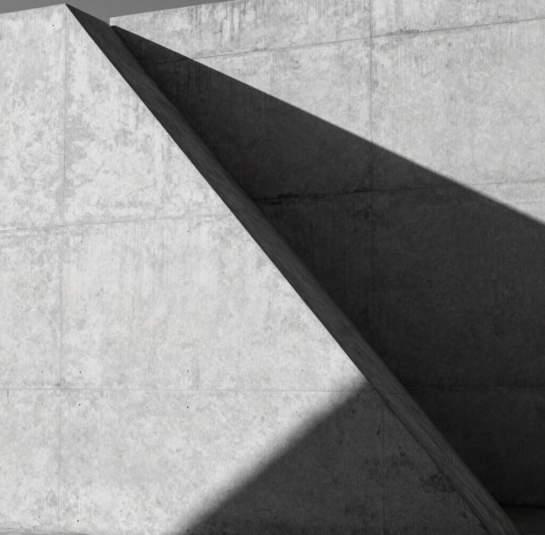 Stark black-and-white architectural geometry, sharp diagonal shadows on a minimalist concrete facade, high-contrast directional light, wide-angle crop.