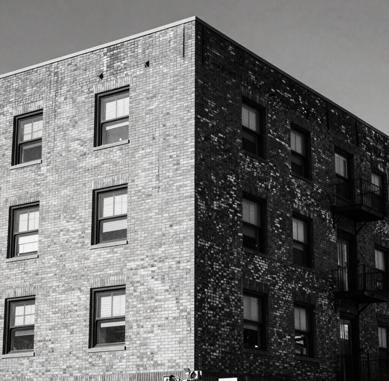 Gritty editorial portrait of a brick residential building under harsh midday Texas sunlight, high-contrast desaturated tones, sharp architectural details, 35mm lens.