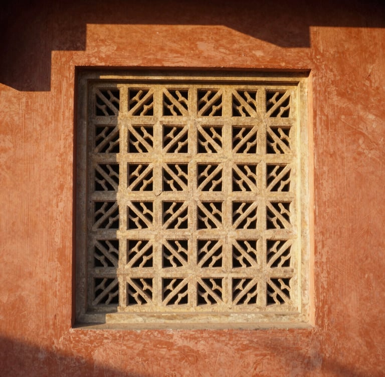 A sun-drenched architectural crop of a stone-carved jali screen at Hotel Grand Capitol, warm golden hour light casting soft shadows on terracotta walls, 35mm photography