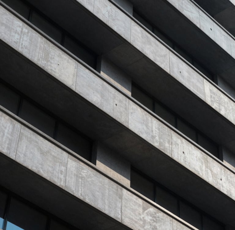A close-up of a high-contrast architectural facade with sharp geometric shadows and clean lines, emphasizing structure and scale under cool diffused light.