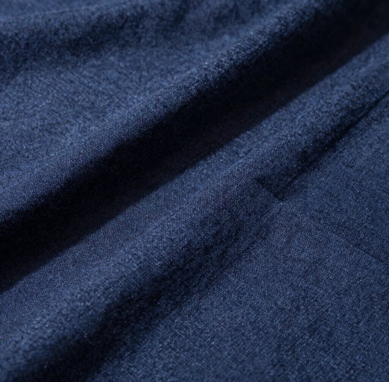 Close-up of heavy linen fabric grain with high-contrast side daylight casting deep shadows on structural seams, 35mm photography