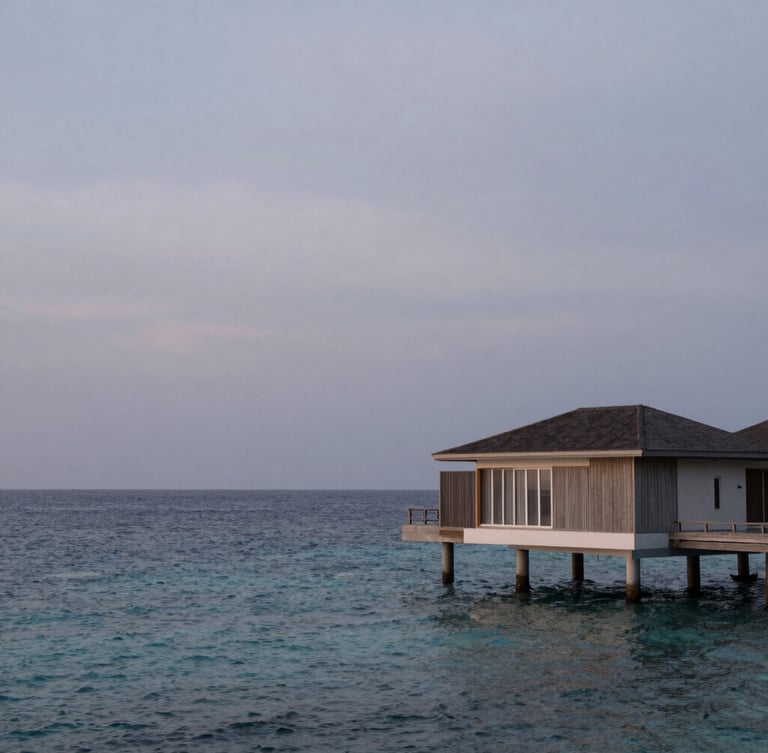Extreme wide environmental shot of a single minimalist overwater villa at twilight, soft overcast light, endless calm ocean, negative space dominating the left side