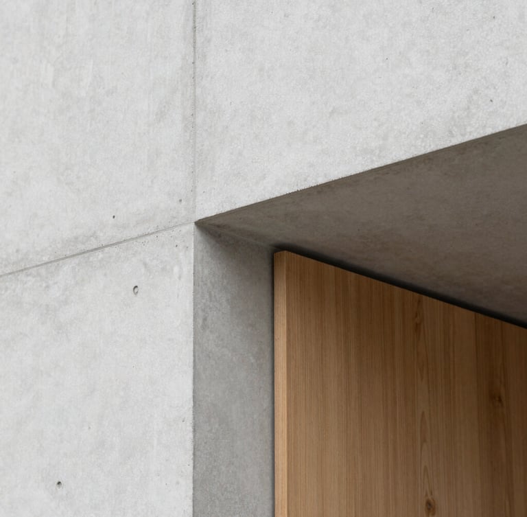 Close-up of a minimalist architectural detail, raw light gray concrete meeting a warm oak wooden panel, clean lines, soft natural overhead lighting, 35mm lens