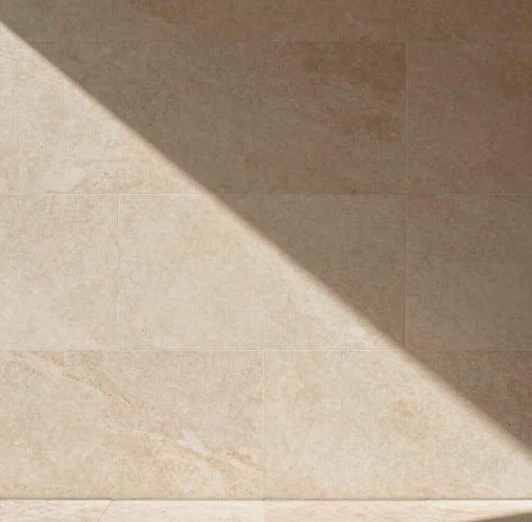 Plano de detalle de un muro de piedra caliza texturizada y hormigón pulido, sombras suaves y geométricas proyectadas de forma natural, estética editorial minimalista.
