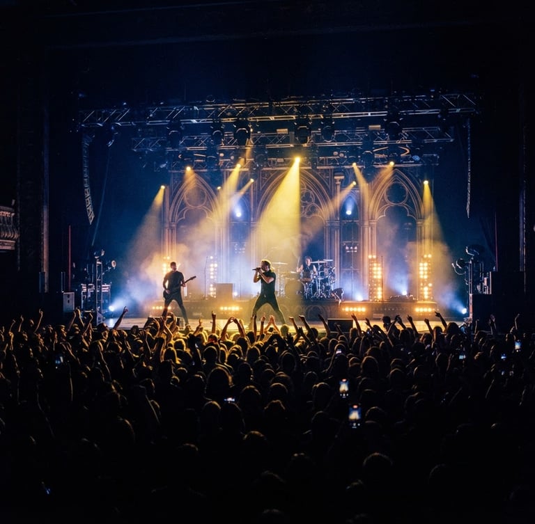 Dramatic wide-angle shot of an illuminated concert stage with deep navy and gold lighting, crowd silhouettes in the foreground, 35mm