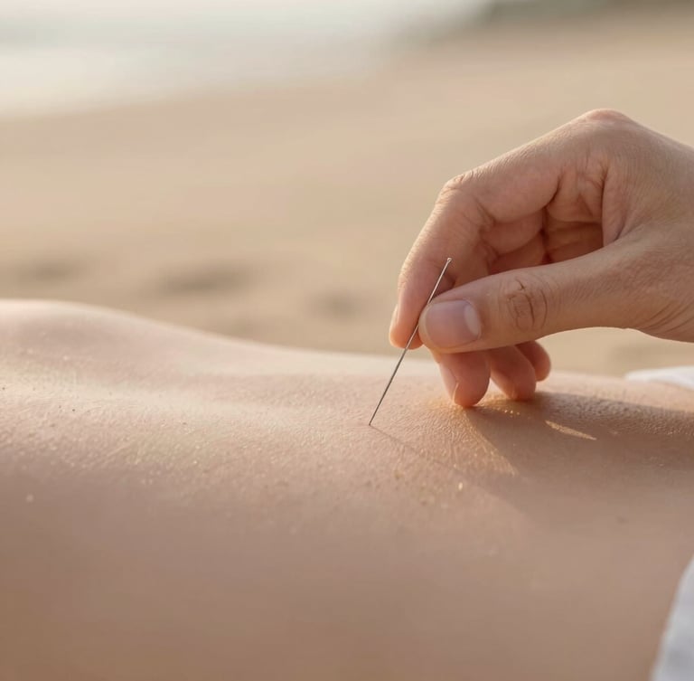 Close-up of a hand placing a single delicate acupuncture needle on a relaxed shoulder, soft golden-hour light, warm sand background, shallow depth of field