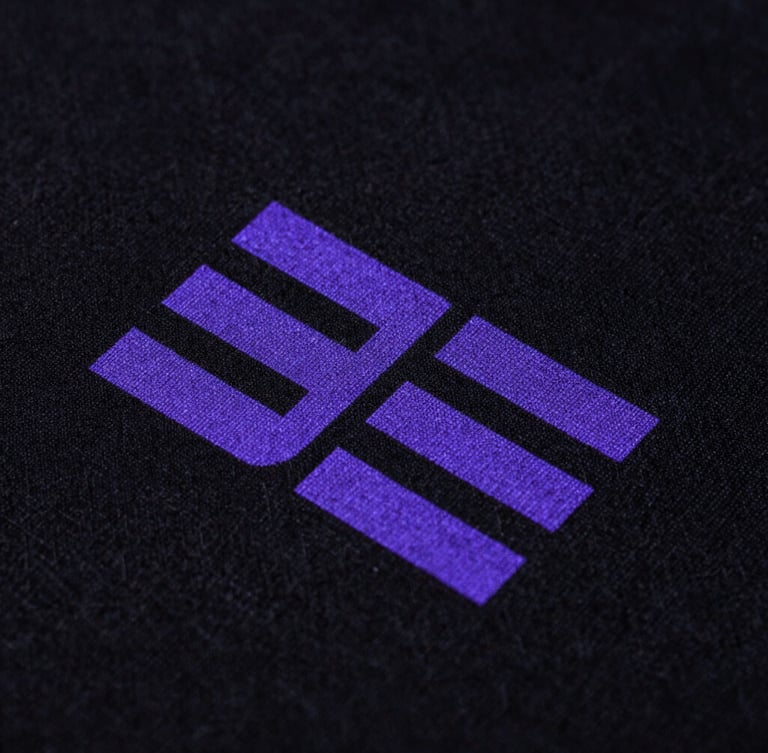 Macro extreme close-up shot of high-density neon purple ink printed on a black heavyweight organic cotton fabric texture, showing the intricate weave and clean print edges, dramatic studio lighting.