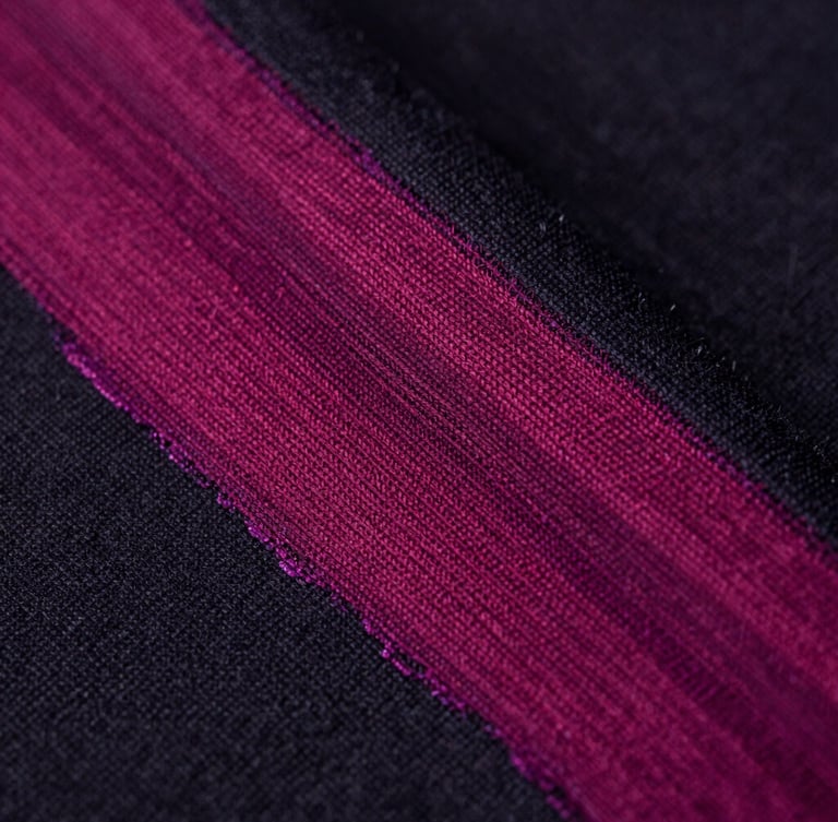 Extreme close-up of vibrant magenta ink on dark cotton fabric, showing rich textile fiber detail under sharp studio lighting, 50mm