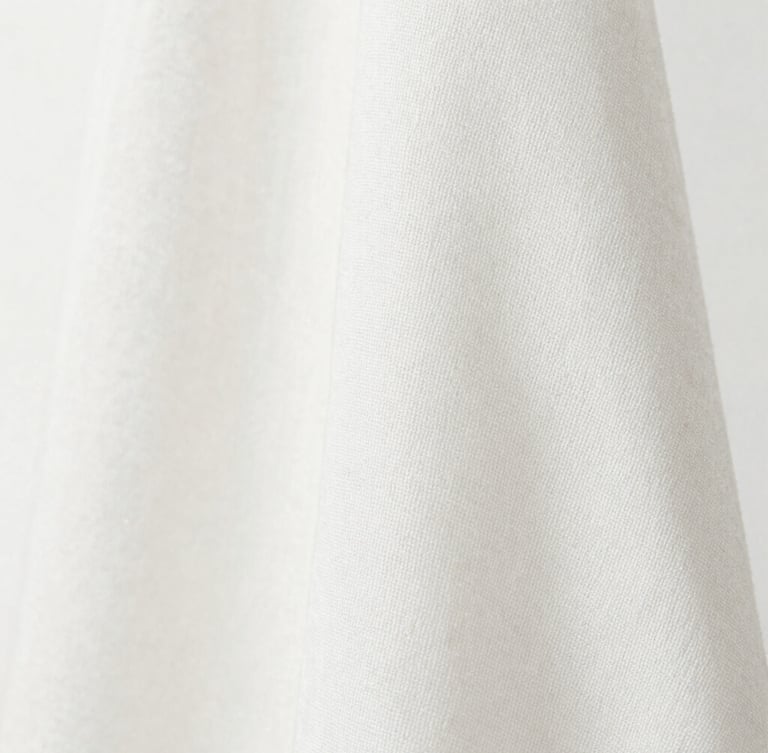 Macro close-up of a finely woven breathable cotton-silk fabric, showing subtle texture and natural drape, soft diffused natural daylight, clean white background, sharp focus, plenty of negative space to the left.