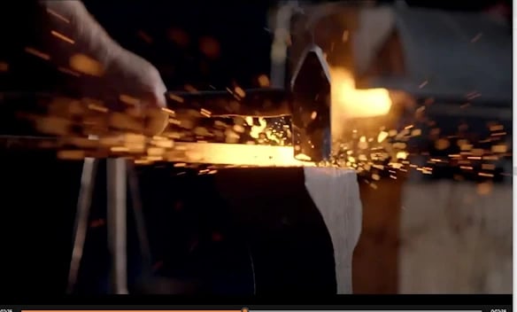 a person is using a hammer on g a piece of metal