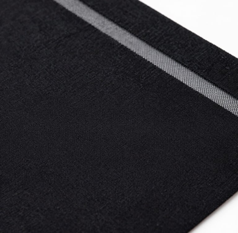 Macro shot of rich black textile ink pressed through a fine silkscreen mesh, high contrast, tactile fabric textures.