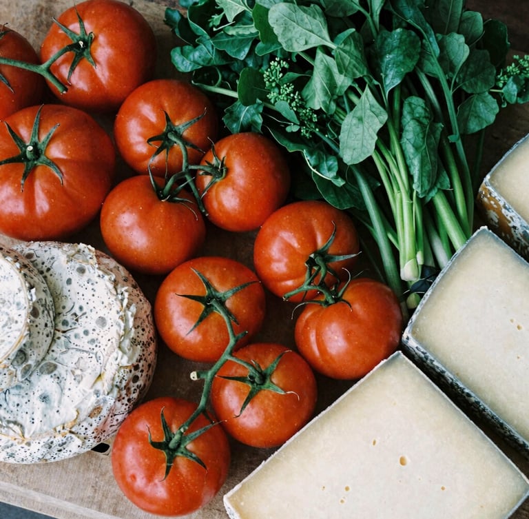 Overhead flat lay of a bustling modern organic food market stall, vibrant heirloom tomatoes and artisanal cheeses, soft natural side-light, Scandinavian editorial style, high-contrast matte finish.