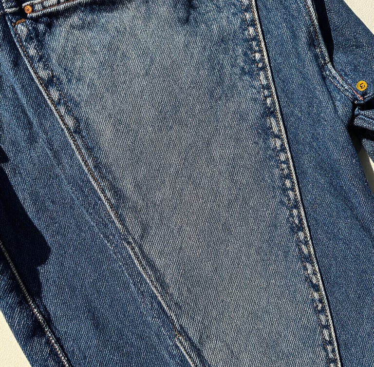 Tactile film photography of raw 14oz Japanese selvedge denim texture, harsh daylight, high contrast, showing deep indigo weave and red selvedge ID line