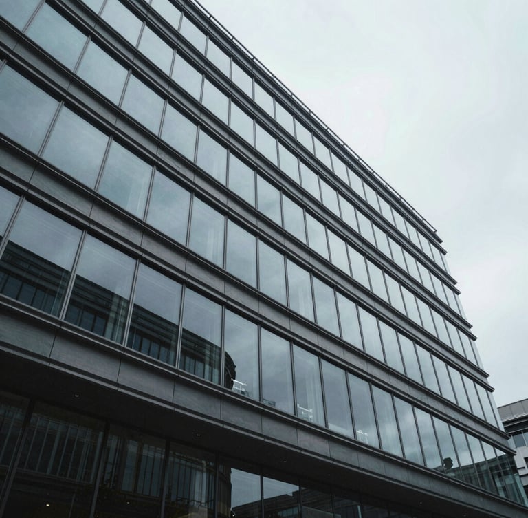 Wide architectural perspective of a modern corporate glass facade, sharp geometric lines, cool overcast daylight.