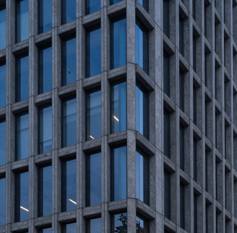 Sharp clean architectural lines of a modern steel and concrete skyscraper facade during twilight blue hour, high-contrast structural details