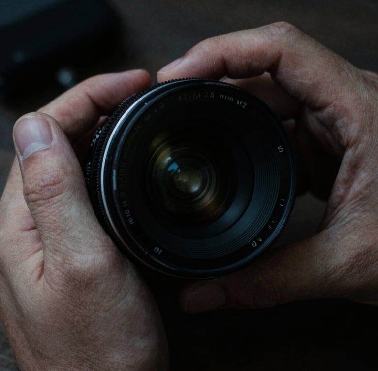 Extreme close-up of hands adjusting a vintage anamorphic camera lens, low-key dramatic lighting, high contrast, 35mm grain