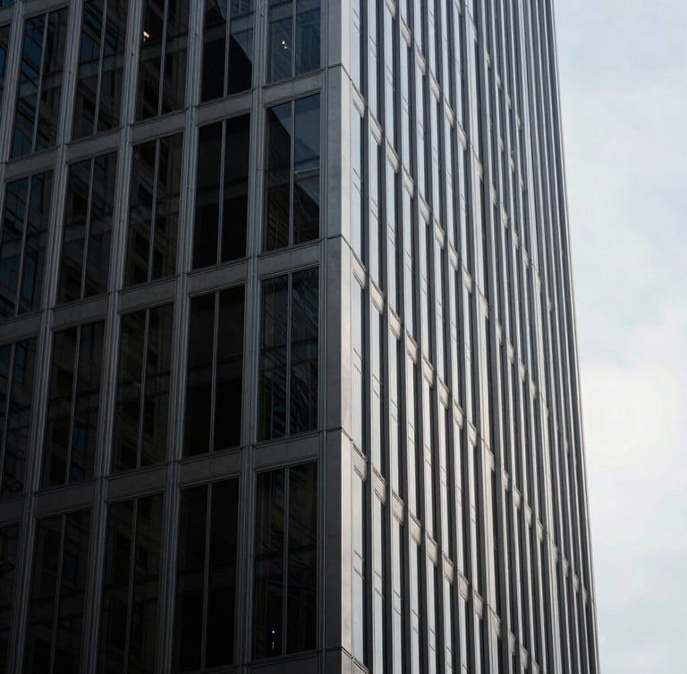 Minimalist architectural close-up of a modern steel and glass skyscraper corner in New York, dramatic high-contrast lighting, deep shadows, clean lines against a pale sky.
