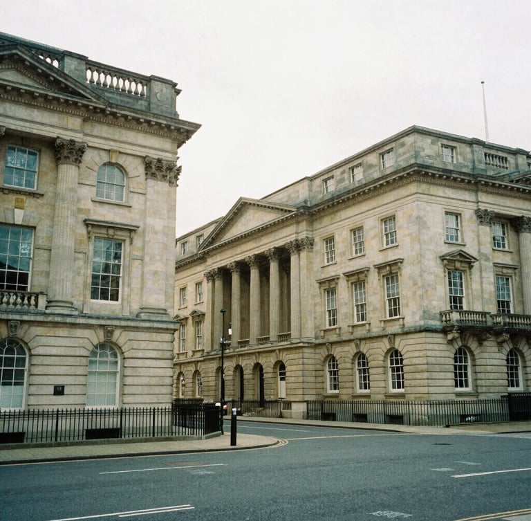 Wide-angle architectural photograph of classic stone financial buildings in Birmingham, soft natural overcast daylight, muted forest green tones, 35mm film grain