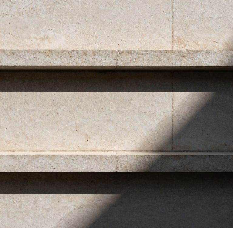 Extreme architectural close-up of a travertine stone facade, sharp geometric shadows from direct sunlight, minimalist composition.