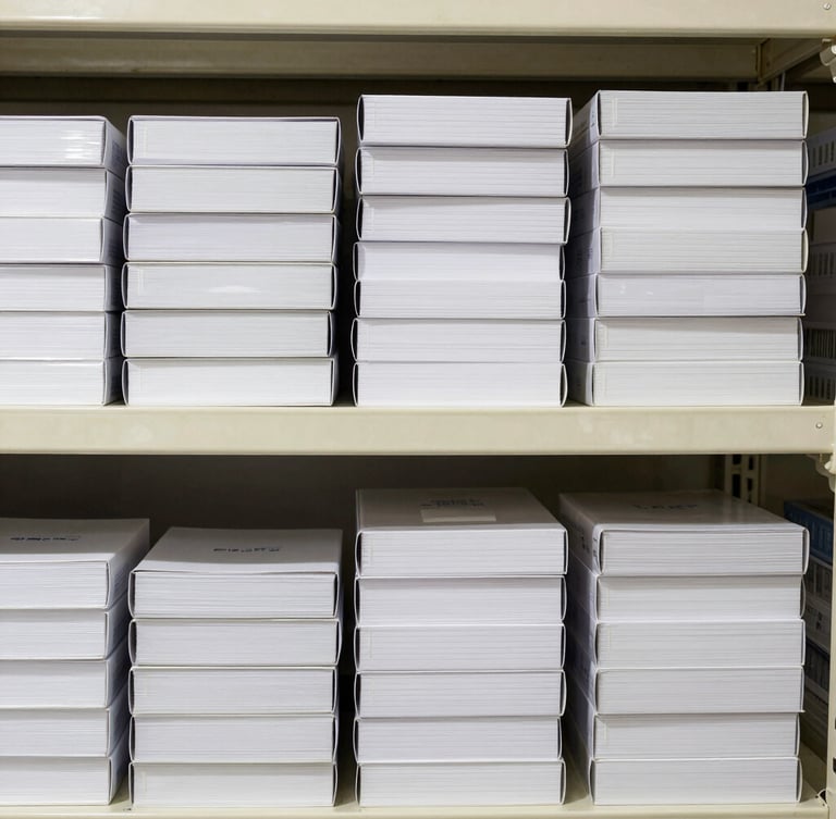 Straight-on flatlay of neatly stacked boxes of commercial stationery and order pads on clean warehouse shelving, bright high-key commercial lighting.