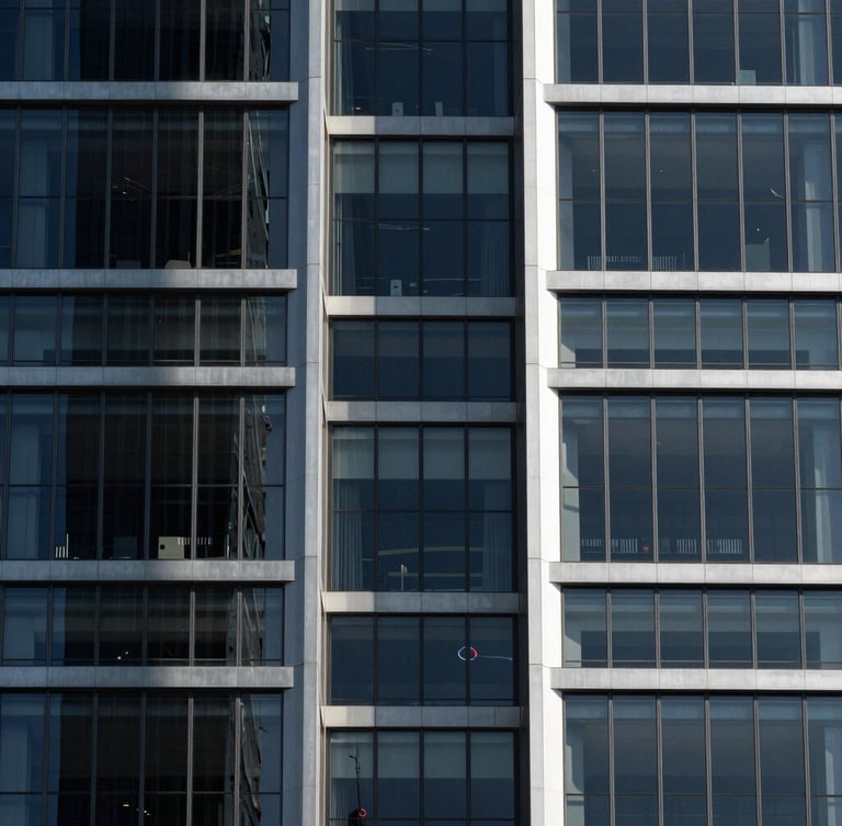 Symmetrical modern skyscraper facade with clean glass panels casting sharp geometric shadows under high-contrast sunlight, 85mm architectural photography.