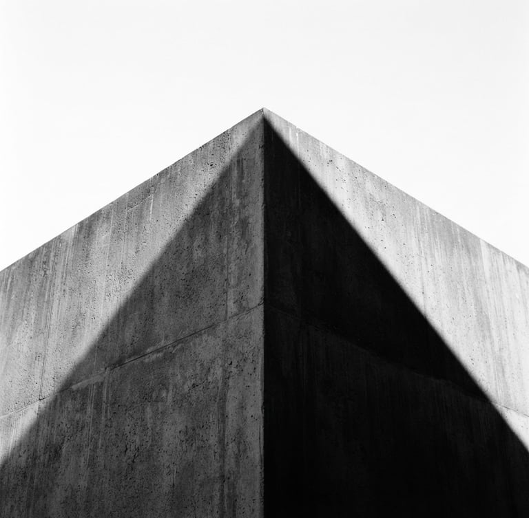 Minimalist architectural photography of a sharp concrete corner against a stark white sky, harsh direct sunlight casting a sharp black diagonal shadow, 35mm lens