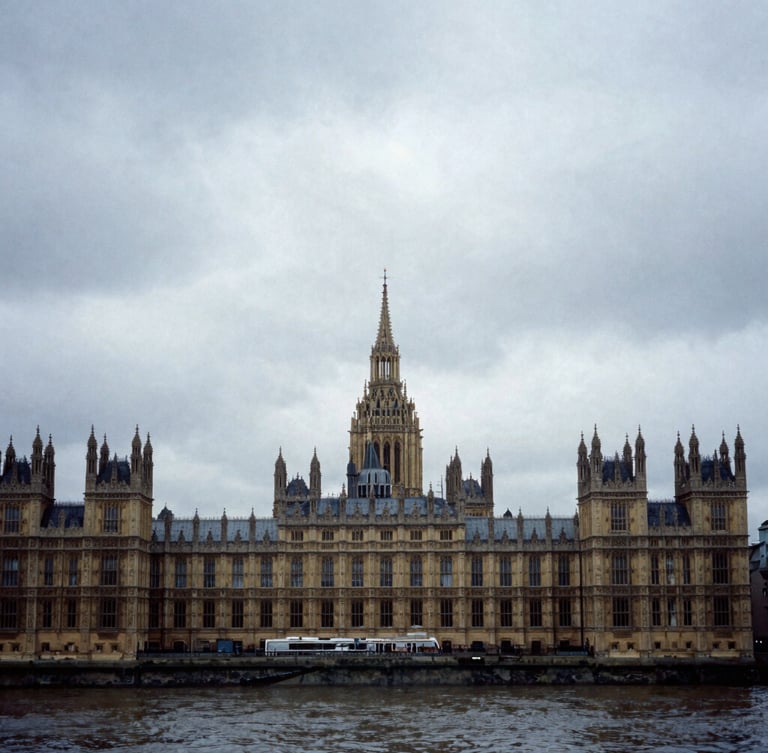 Wide photojournalistic shot of the Palace of Westminster under heavy overcast British skies, moody cool-toned shadows, 35mm gritty documentary style.