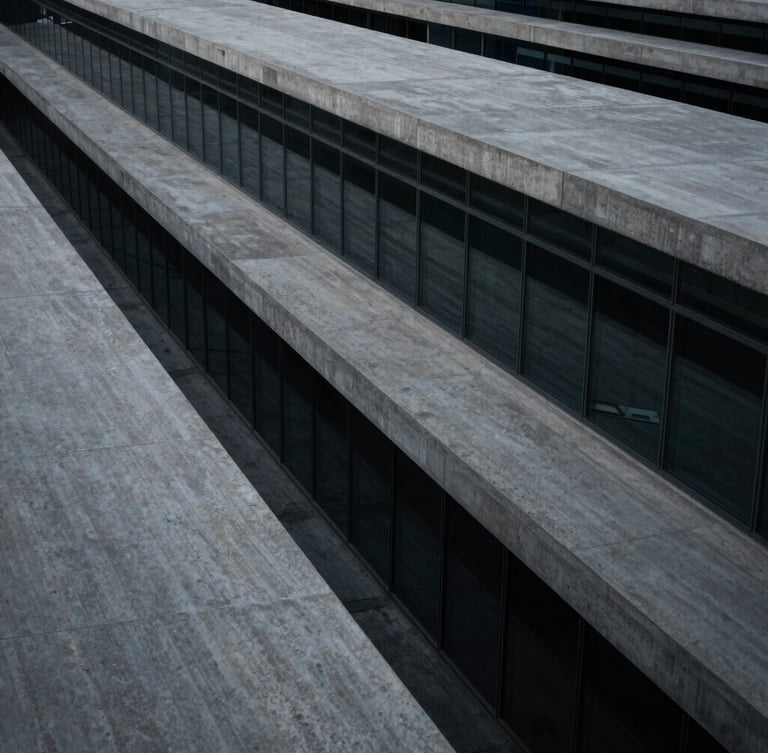 Wide panoramic high-angle architectural perspective of concrete and glass lines, low-key cool-toned lighting, deep graphite shadows.
