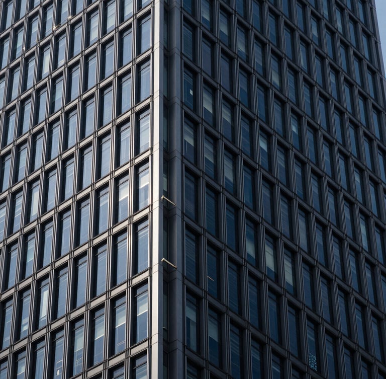 Architectural close-up of a modern steel skyscraper meeting a glass facade, dramatic high-contrast lighting, deep navy tones, crisp geometric lines, 35mm lens