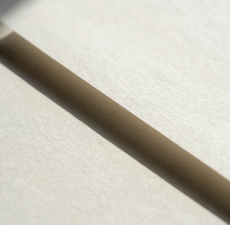 Macro close-up of heavy-weight cotton paper document with sharp geometric shadow cast across the page