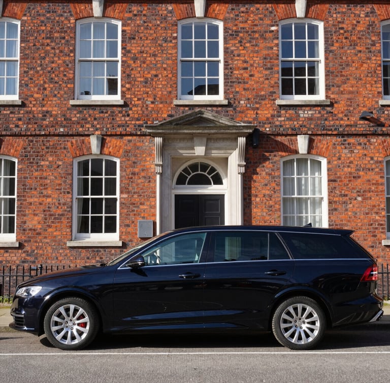 A polished black executive transport vehicle parked in front of a historic brick building in Portsmouth, crisp morning daylight, sharp focus