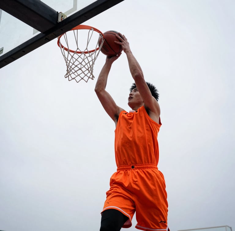 Low-angle dynamic shot of a young basketball player driving to the hoop, high contrast natural light, safety orange jersey, determination, 35mm