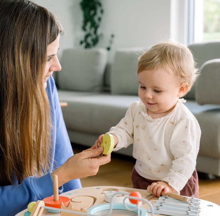 Una niñera profesional de la agencia Nanny Heart, y una niña pequeña, juegan en casa con una mesa de