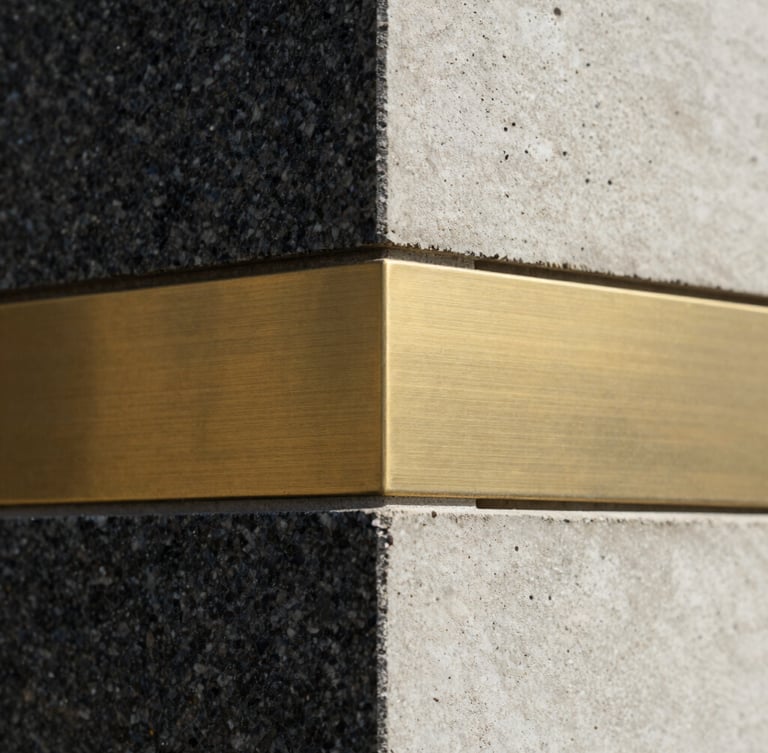 Extreme close-up of premium textured raw materials, dark granite, brushed brass, and cast concrete meeting at a sharp geometric angle, dramatic architectural lighting