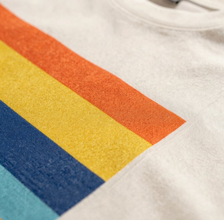 Close-up macro shot of premium t-shirt fabric texture and crisp, vibrant graphic print stitching, warm natural daylight, shallow depth of field.