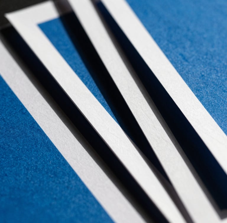 Extreme close-up of high-contrast physical brand collateral, sharp paper edges, direct hard sunlight, deep charcoal shadows, cool blue ink.